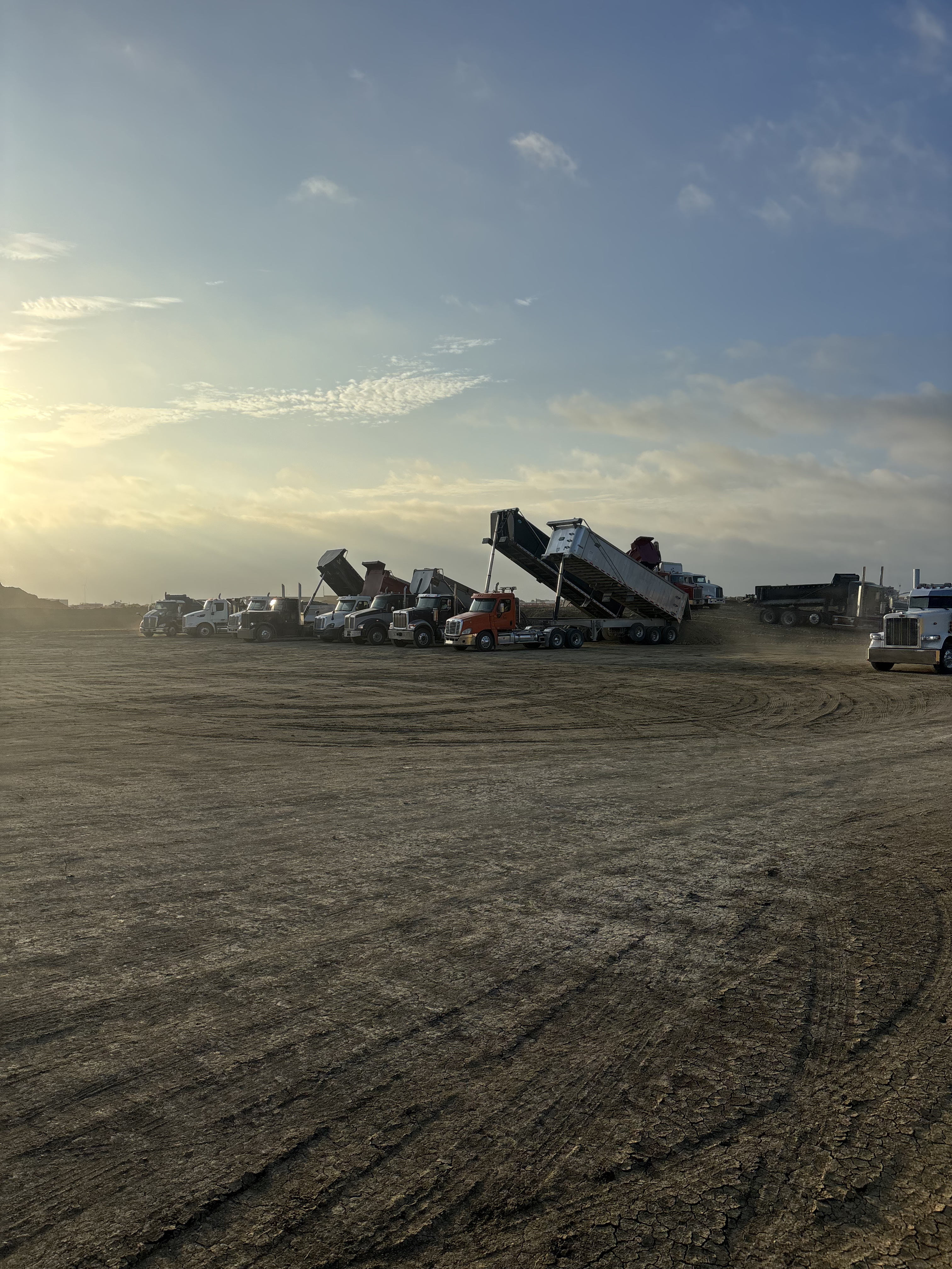 Fleet of heavy-duty commercial dump trucks and trailers parked at an industrial lot near Hubbard, TX