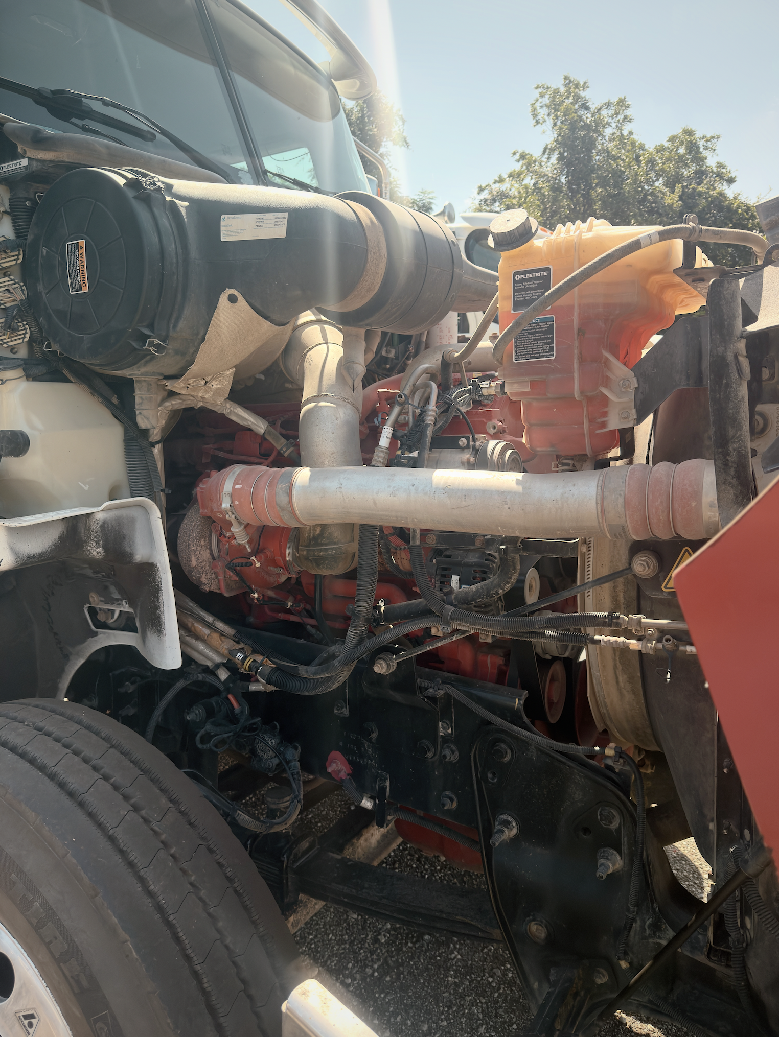 Exposed diesel engine bay with air intake, coolant reservoir, and wiring harnesses during professional diagnostics