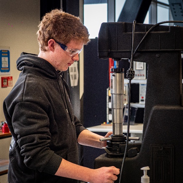 Rhys, an Earn as You Learn learner, operating industrial machinery in a workshop