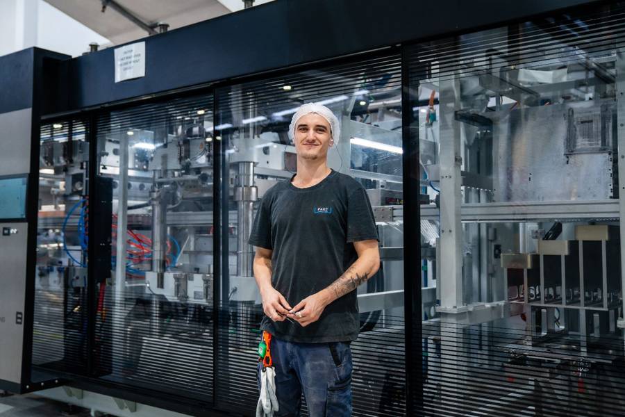Young man standing in front of automated manufacturing machinery