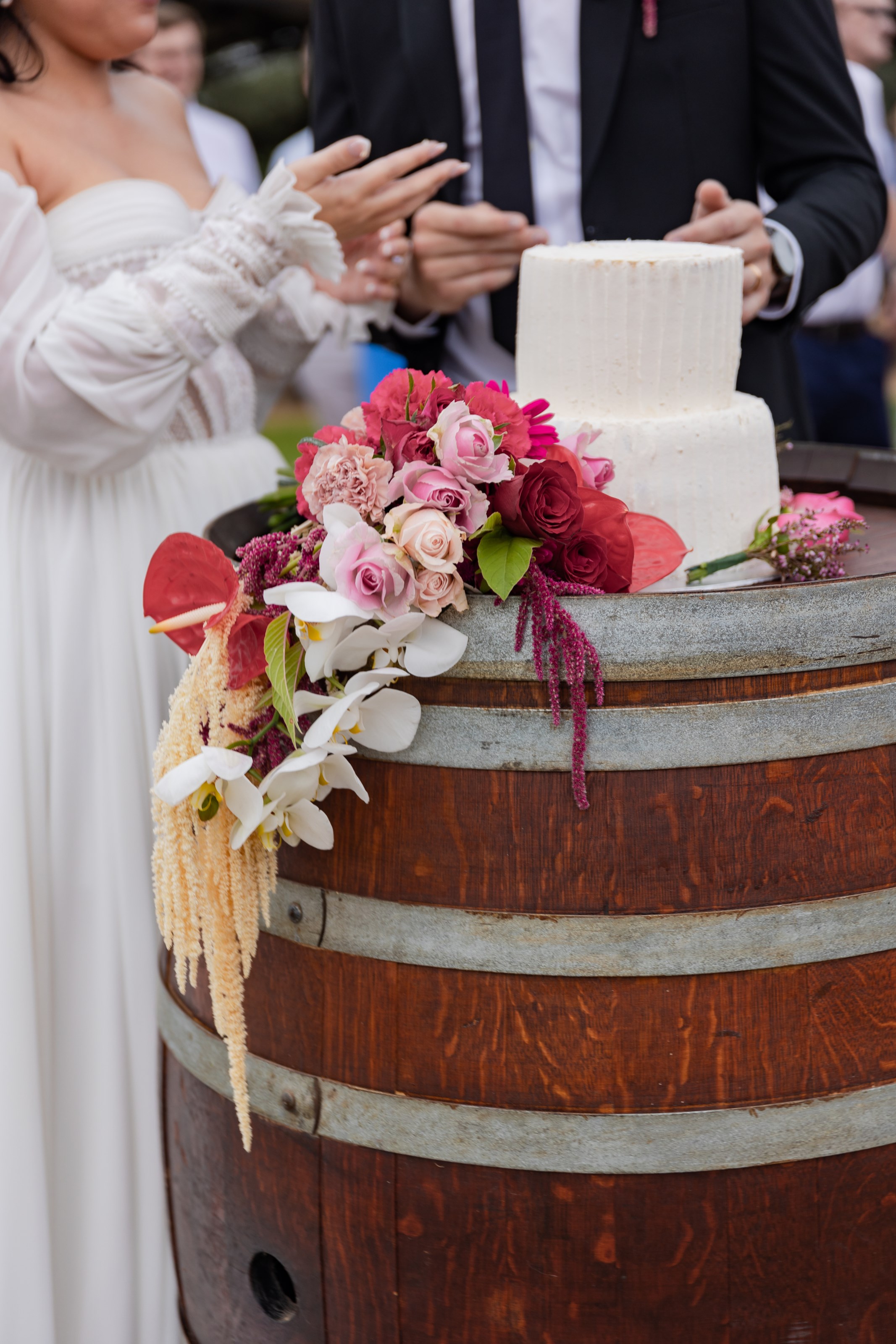 Two-tier wedding cake on a wine barrel with cascading florals