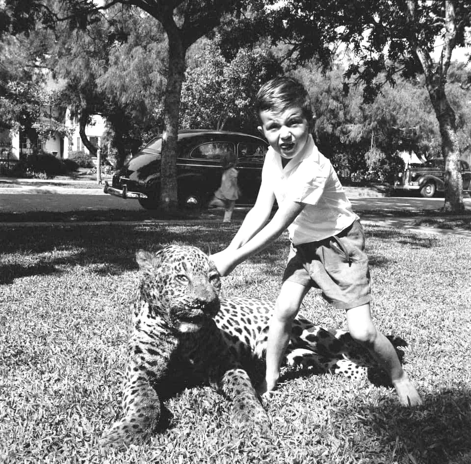 Historical photo: Child with young jaguar in captivity, early 1900s