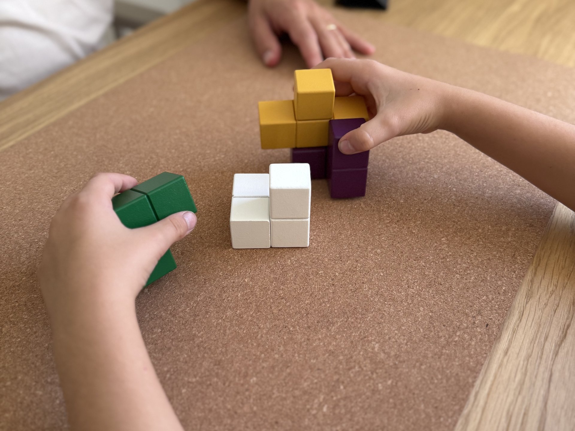 Kinderhände beim Bauen mit Holzwürfeln in der Ergotherapie
