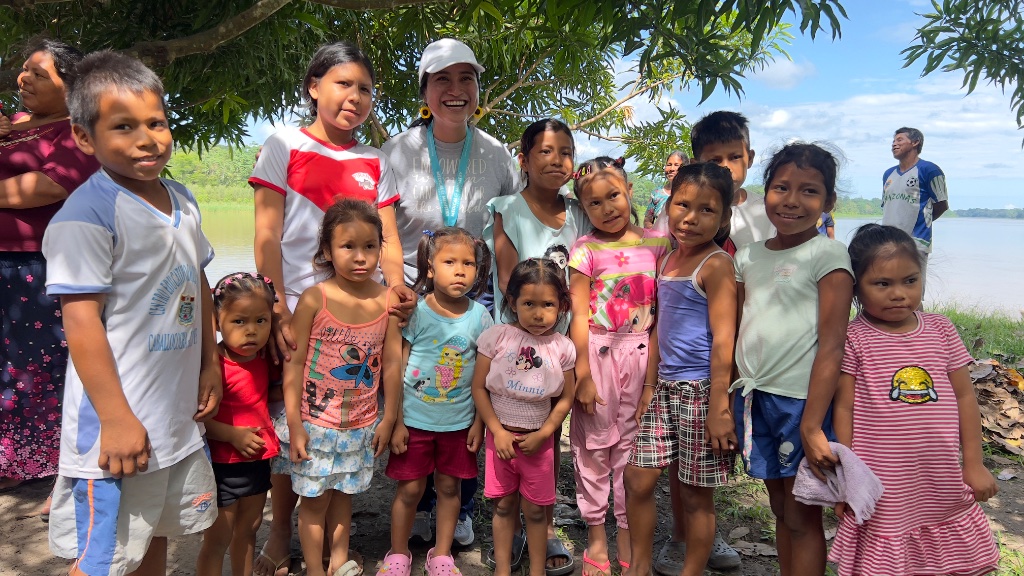 Across the Amazon — a group of village children gathered with a teacher near the river