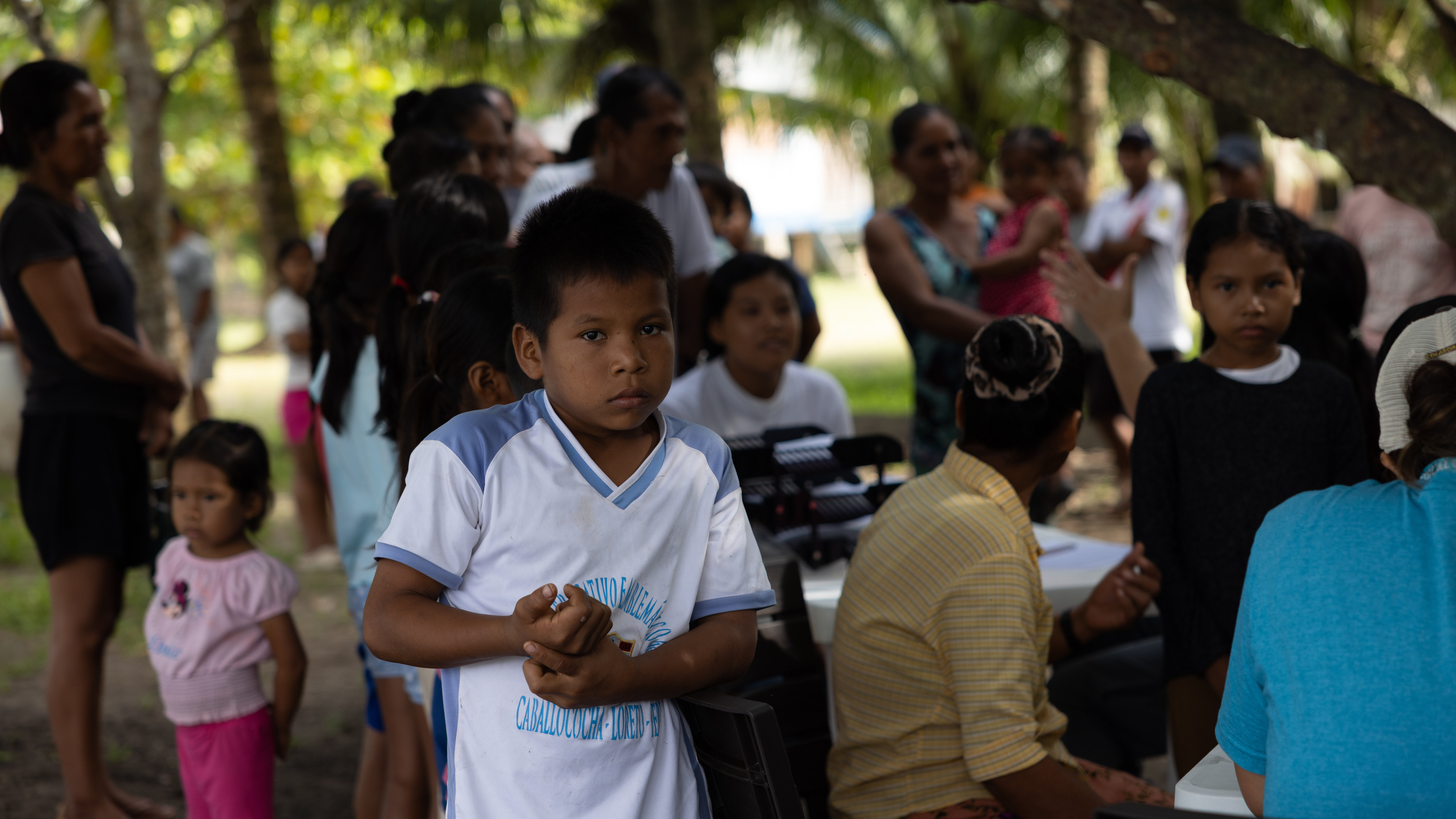 A young boy looking directly at the camera during an Amazon community gathering