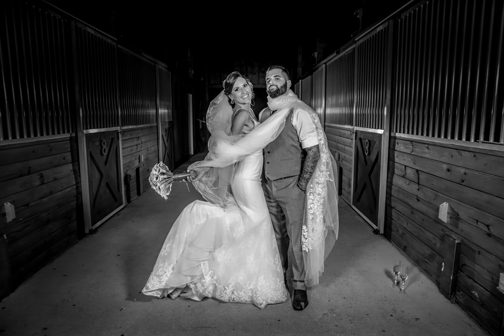 A bride and groom framed in a stable corridor