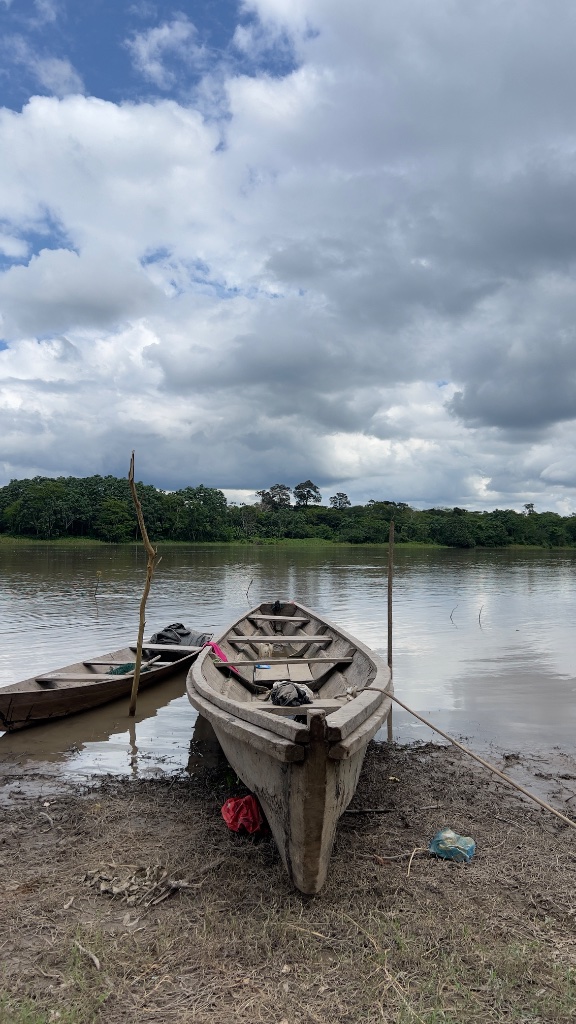 Across the Amazon — a wooden canoe tied up at a muddy riverbank