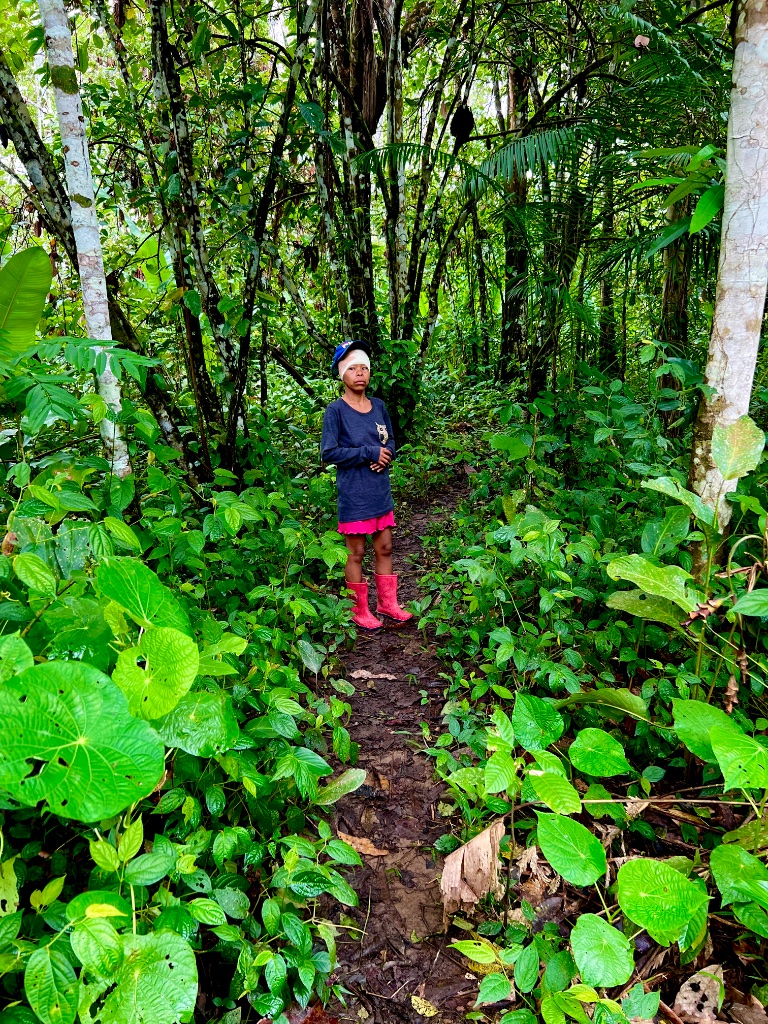 Across the Amazon — a child standing on a jungle path in pink boots