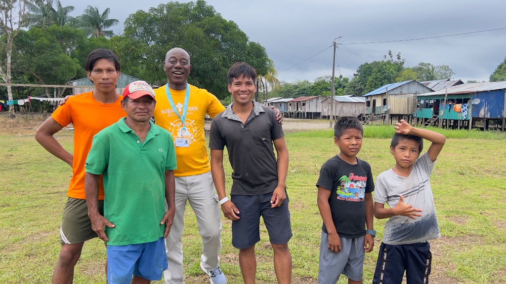 Across the Amazon — a family standing in front of raised wooden stilt houses in the village