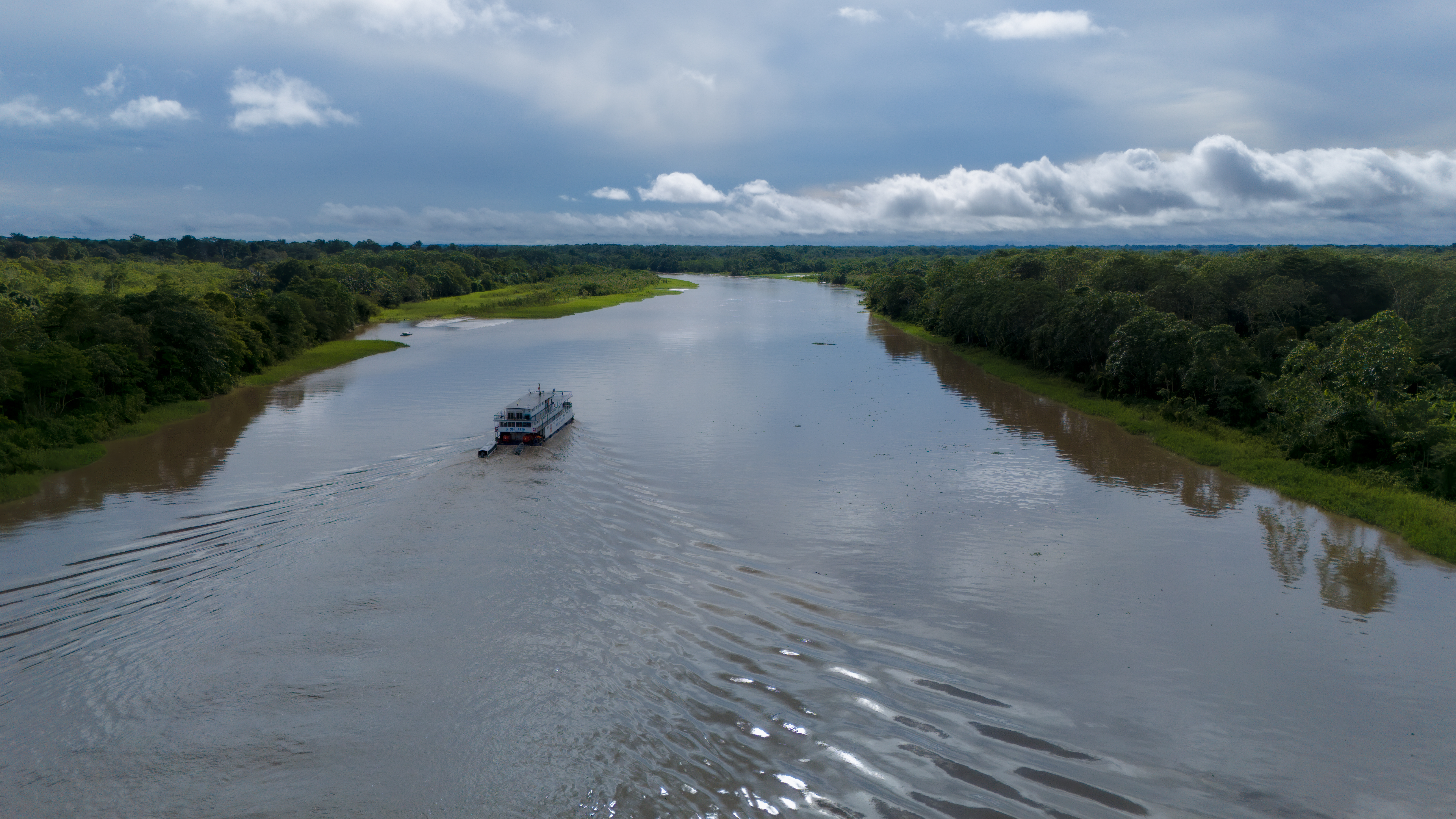 Aerial view of an Amazon river with a boat traveling through the rainforest