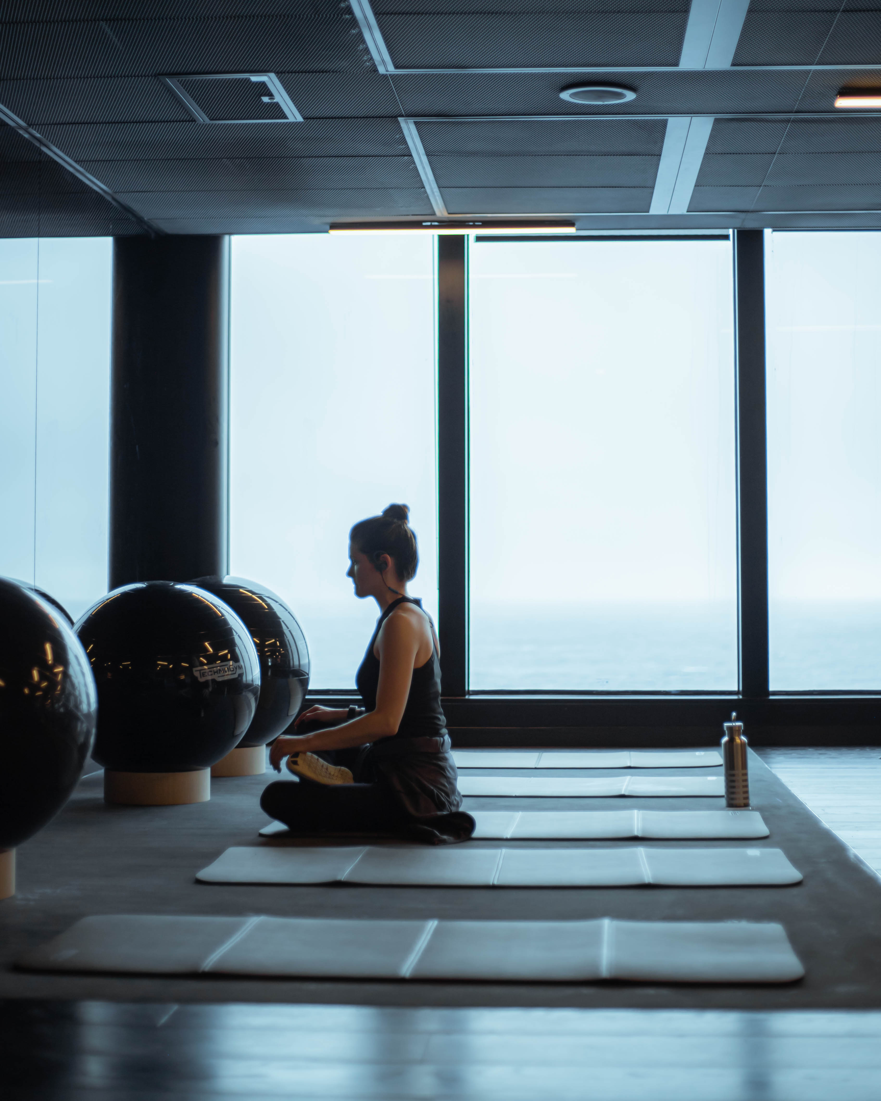 A leader in meditation aboard a Virgin Voyages ship, floor-to-ceiling windows over the sea