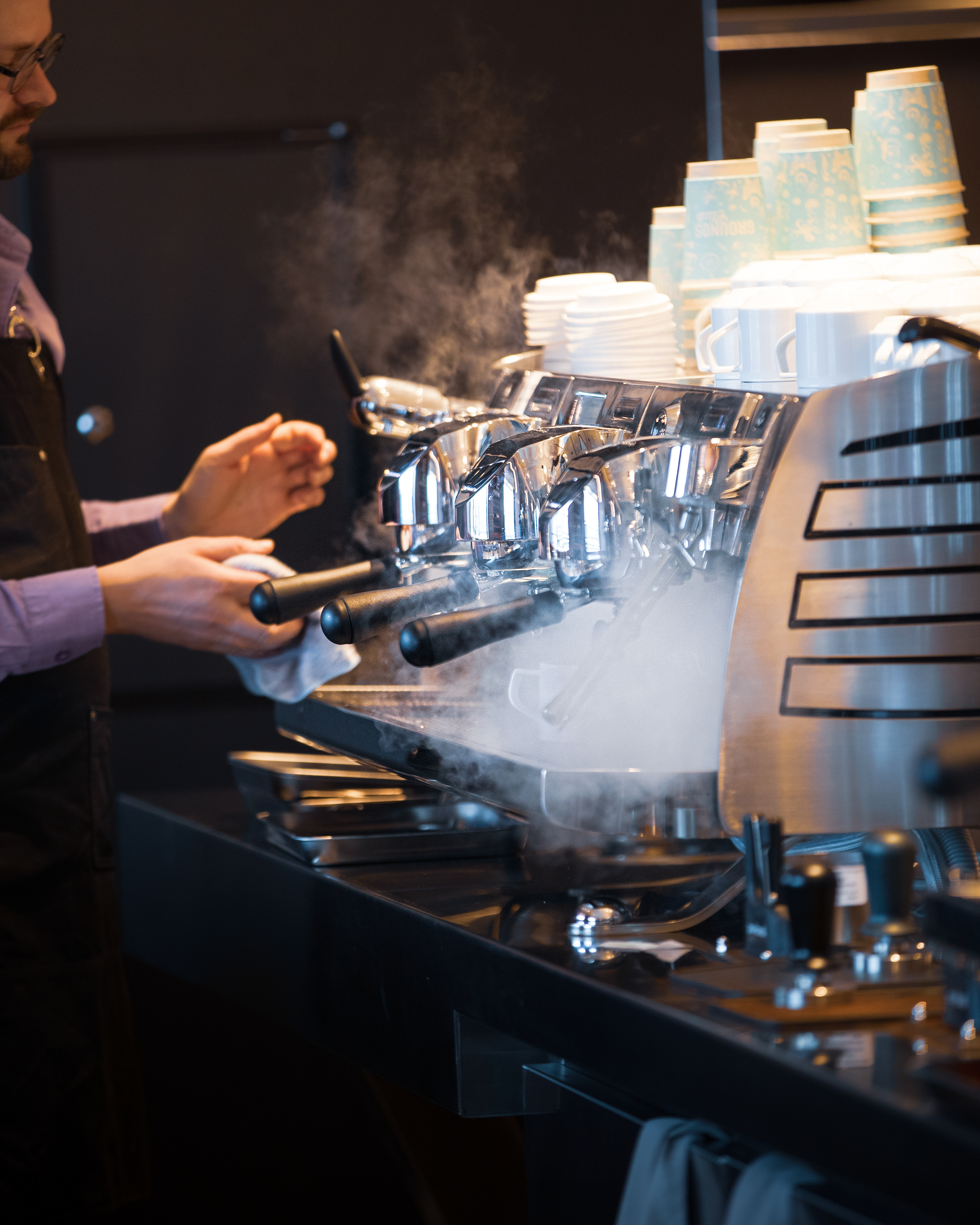 A barista steaming a chrome espresso machine aboard a Virgin Voyages ship