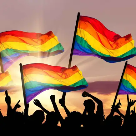 Pride flags at sunset — the growing visibility of safe spaces for gay massage Crowd holding rainbow pride flags at sunset, symbolizing the growing visibility and safe spaces of the LGBTQ+ community and M4M massage therapy