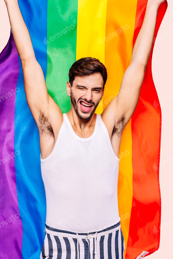 Happy gay man celebrating body positivity and self-acceptance with pride flag background