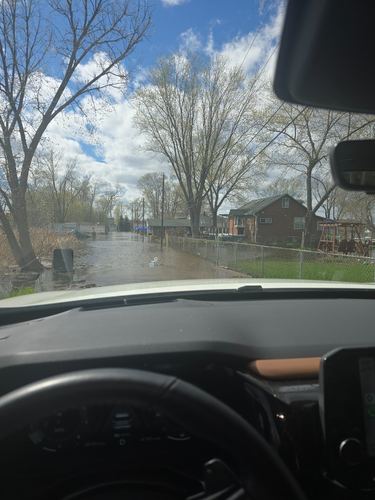 Flooded street in the Chain O' Lakes area with rising water levels approaching homes