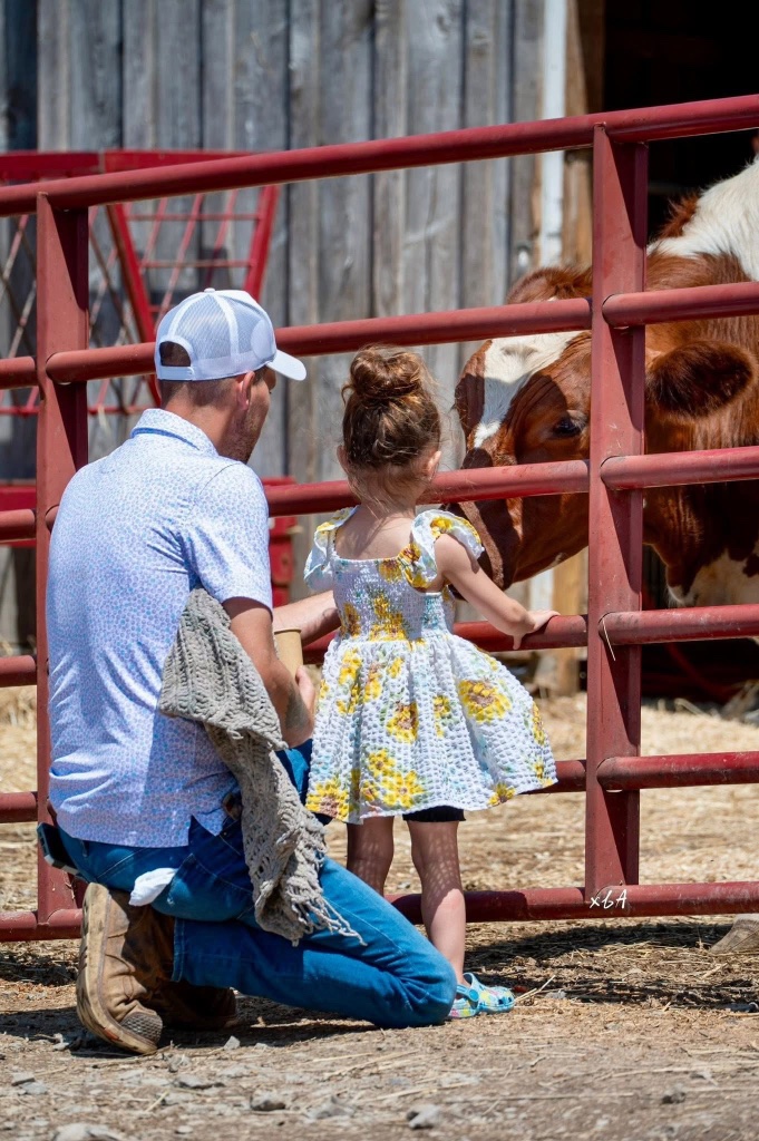 A father and daughter greeting a cow at Asha's Farm Sanctuary