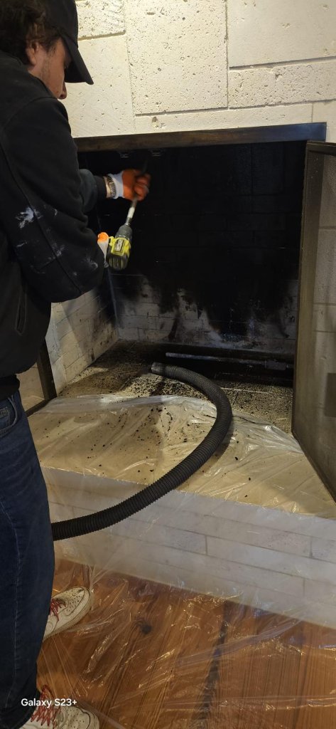 Chimney sweep cleaning soot from a fireplace