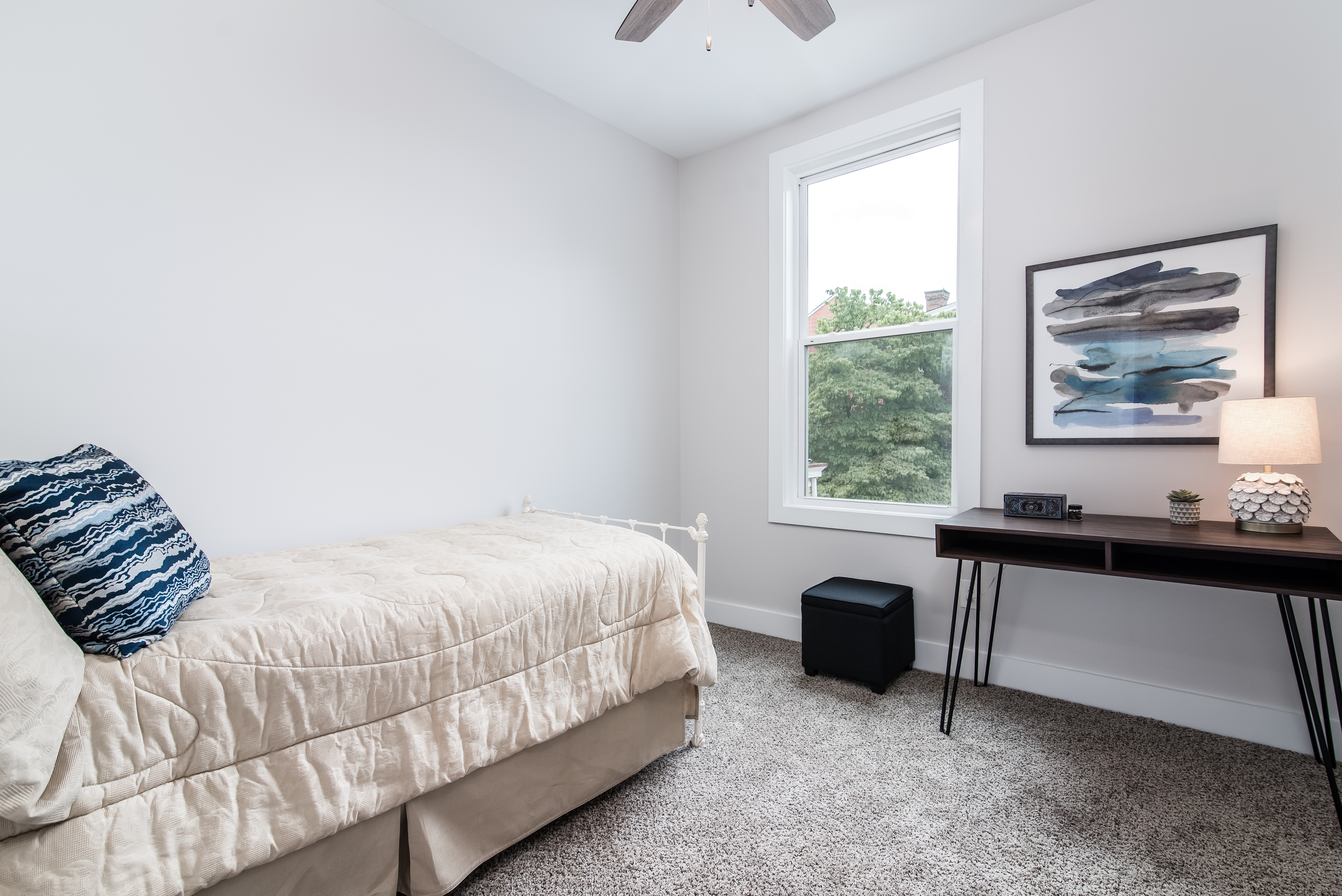 Bedroom with twin bed, window, and desk workstation