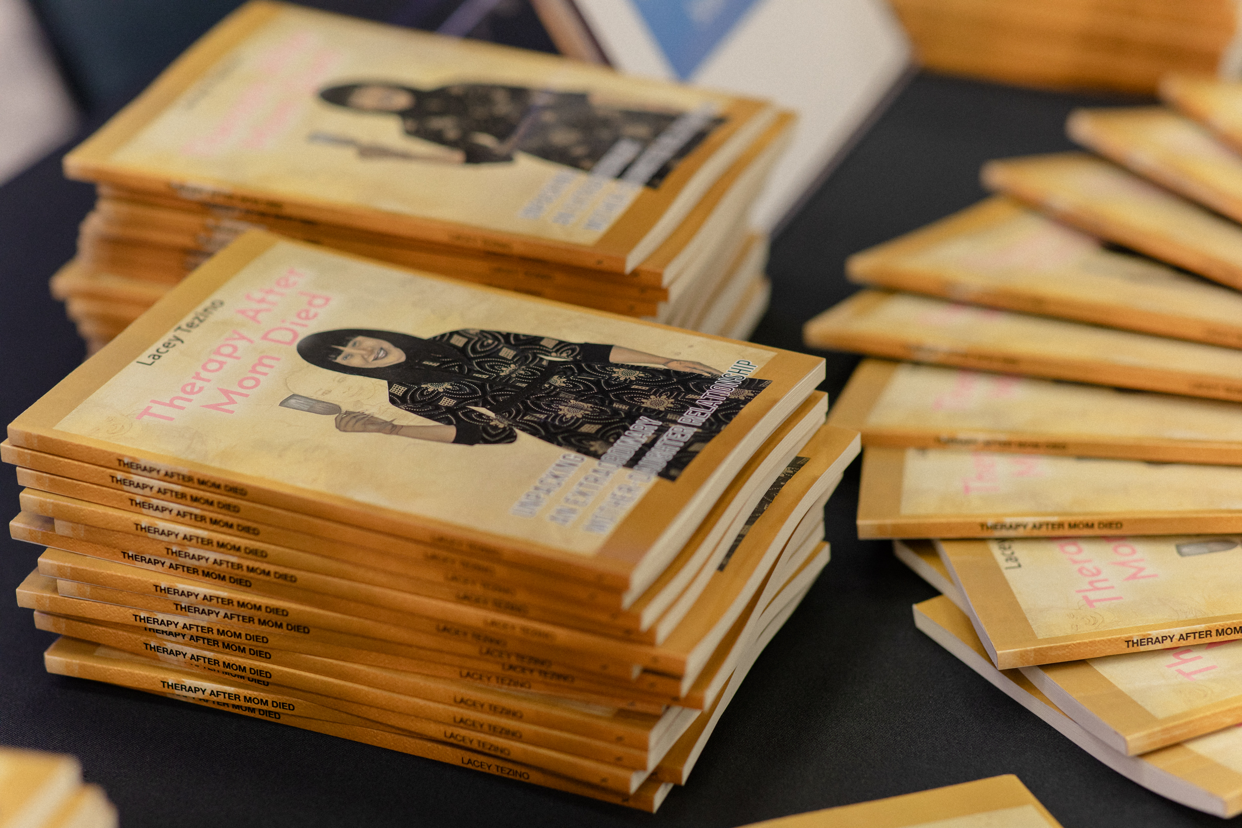 Signed paperback copies of Therapy After Mom Died stacked on a table