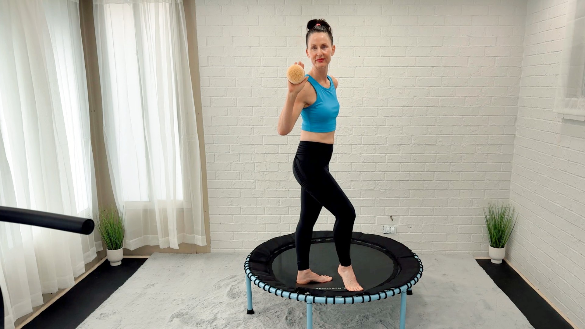 Angie Balgemann standing on a rebounder holding a dry brush