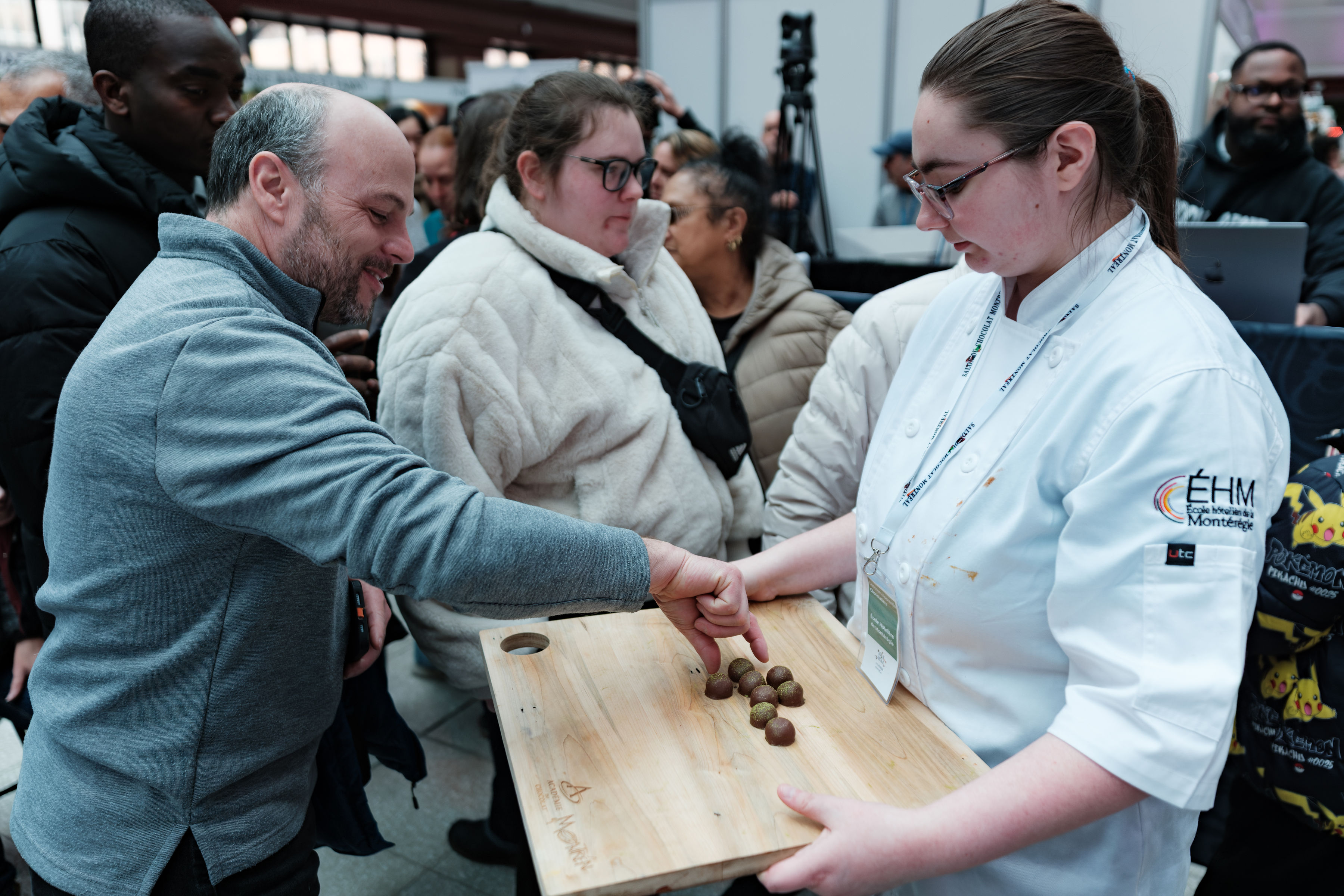 A chocolatier sharing handmade chocolates with a visitor at the Salon du Chocolat