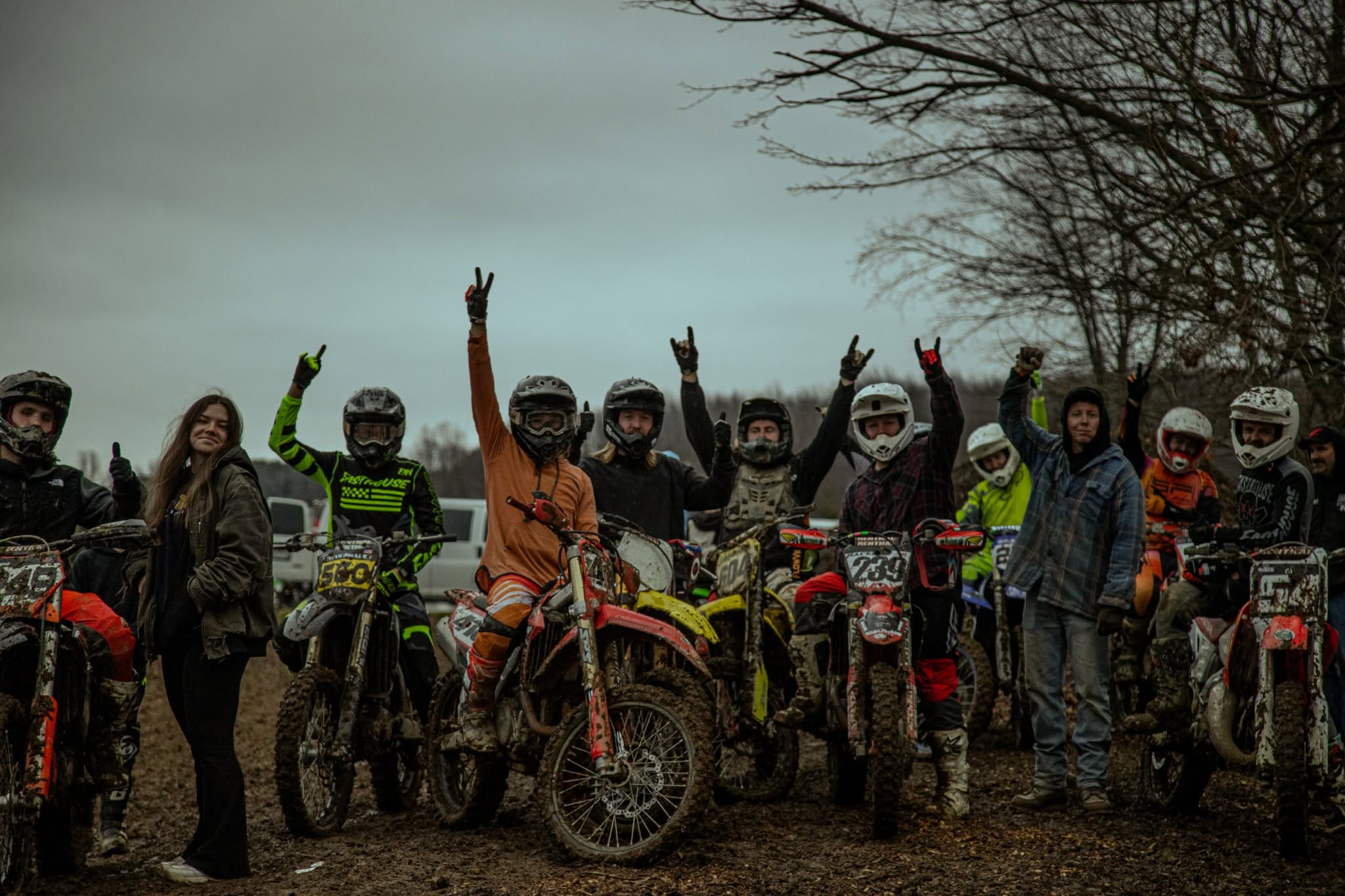 Speed Farm motocross training group with riders and mud-covered bikes on a gloomy track day
