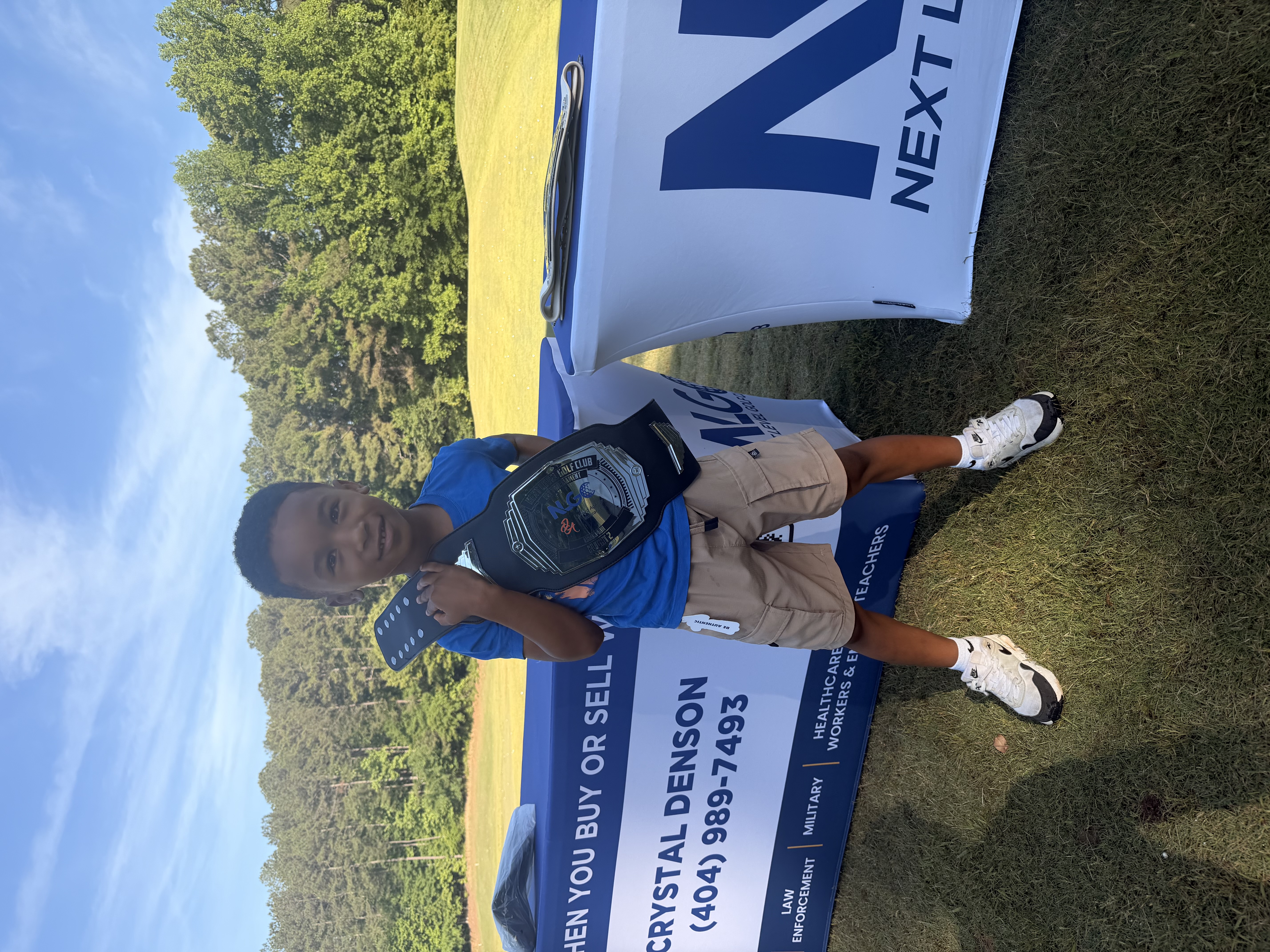 Young golfer with a championship belt at a Next Level Golf Club event