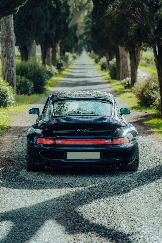 Schwarzer Porsche Turbo auf Allee