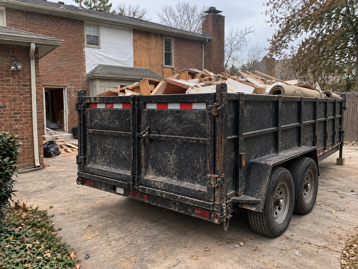 Dump trailer loaded with demolition debris outside a home being gutted.