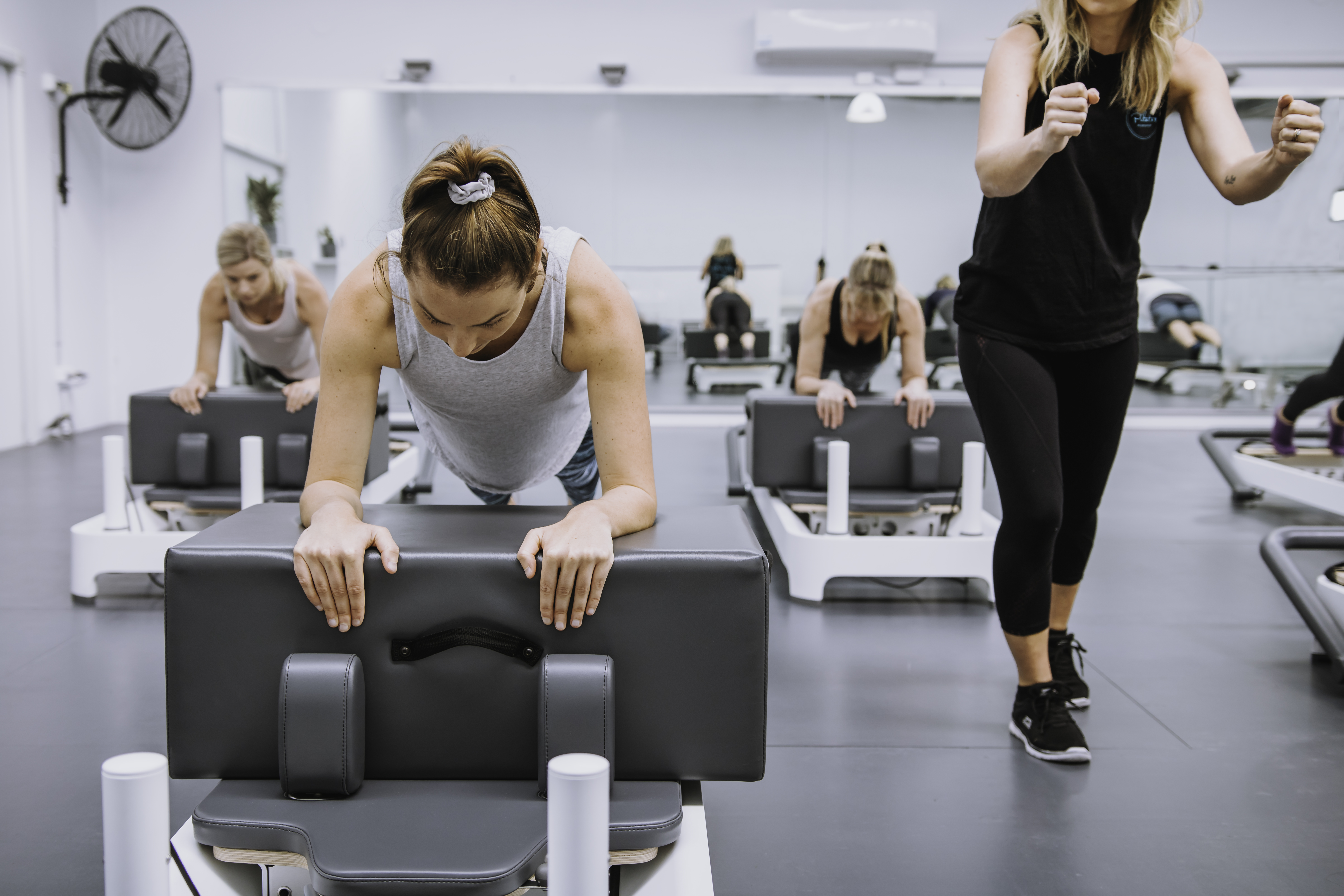 Pilates instructor guiding a client through a reformer exercise