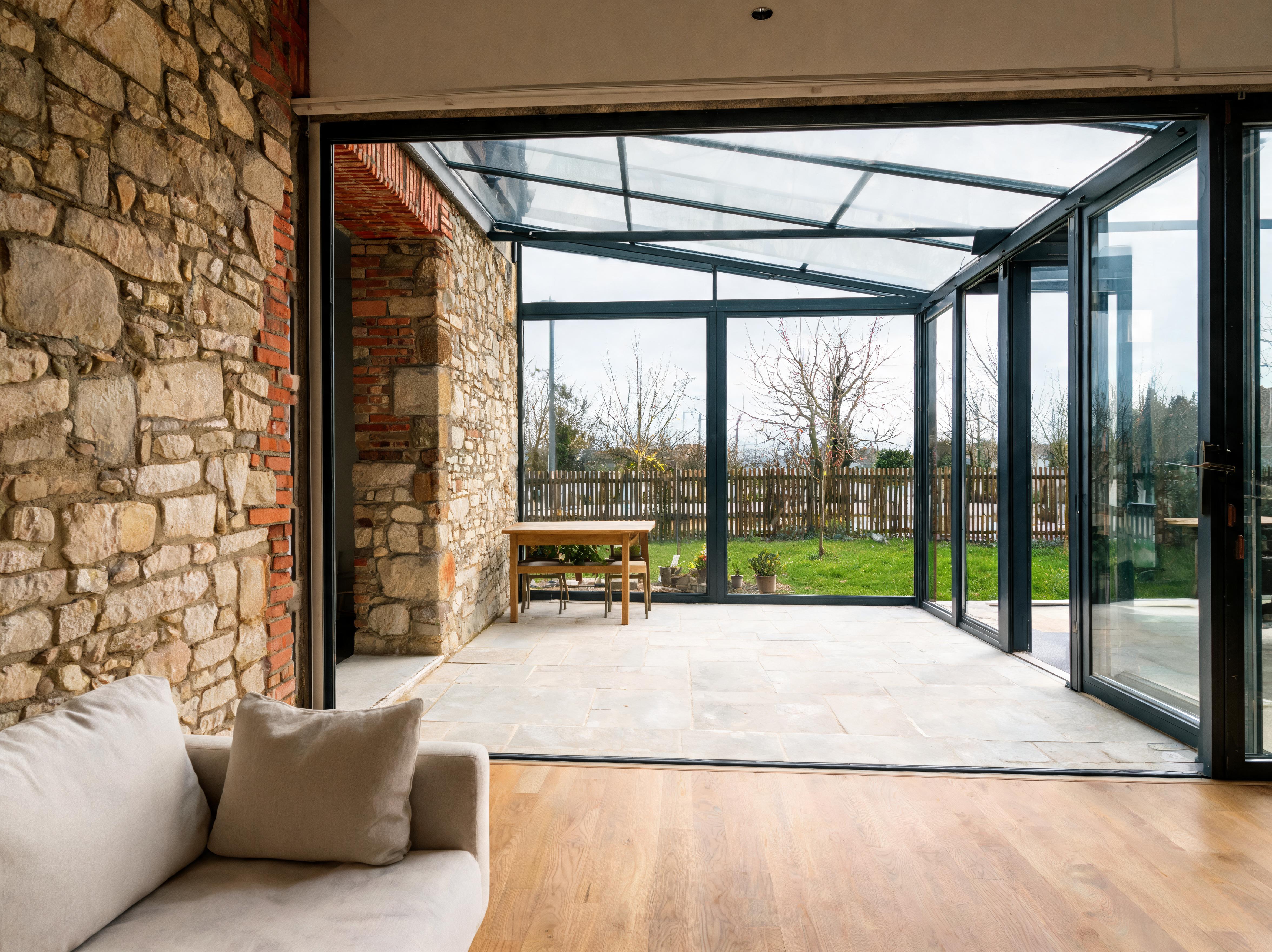 Vue intérieure de la maison en meulière rénovée ouverte sur sa véranda et le jardin
