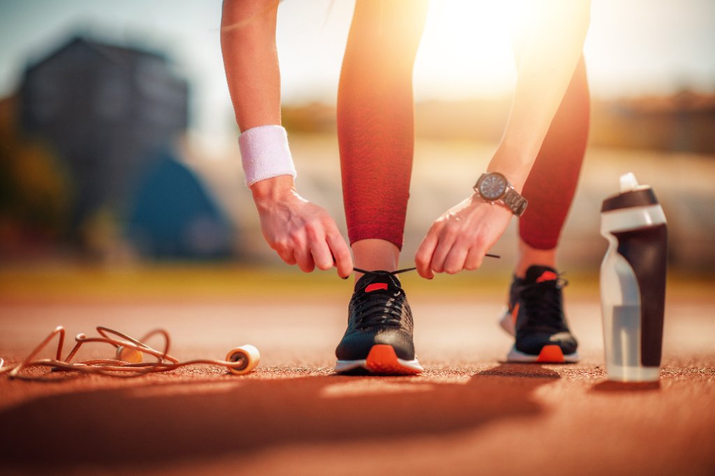 Athlete tying running shoes on an outdoor track at golden hour
