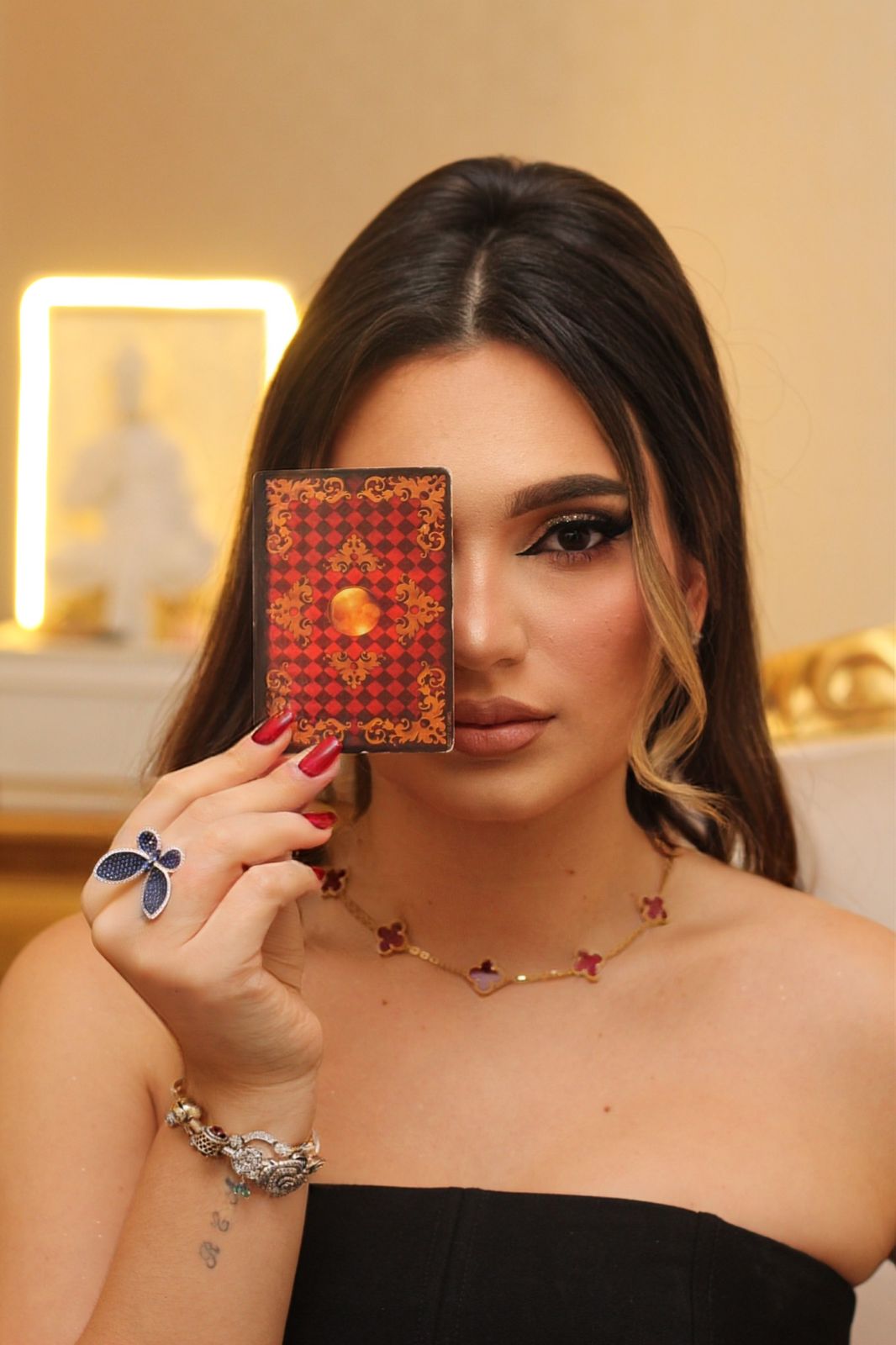 Milena com carta de tarot sobre o olho