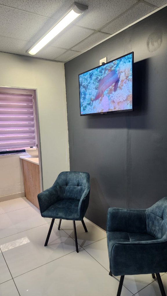 Waiting area with blue armchairs, TV and vanity alcove at Cleanse clinic