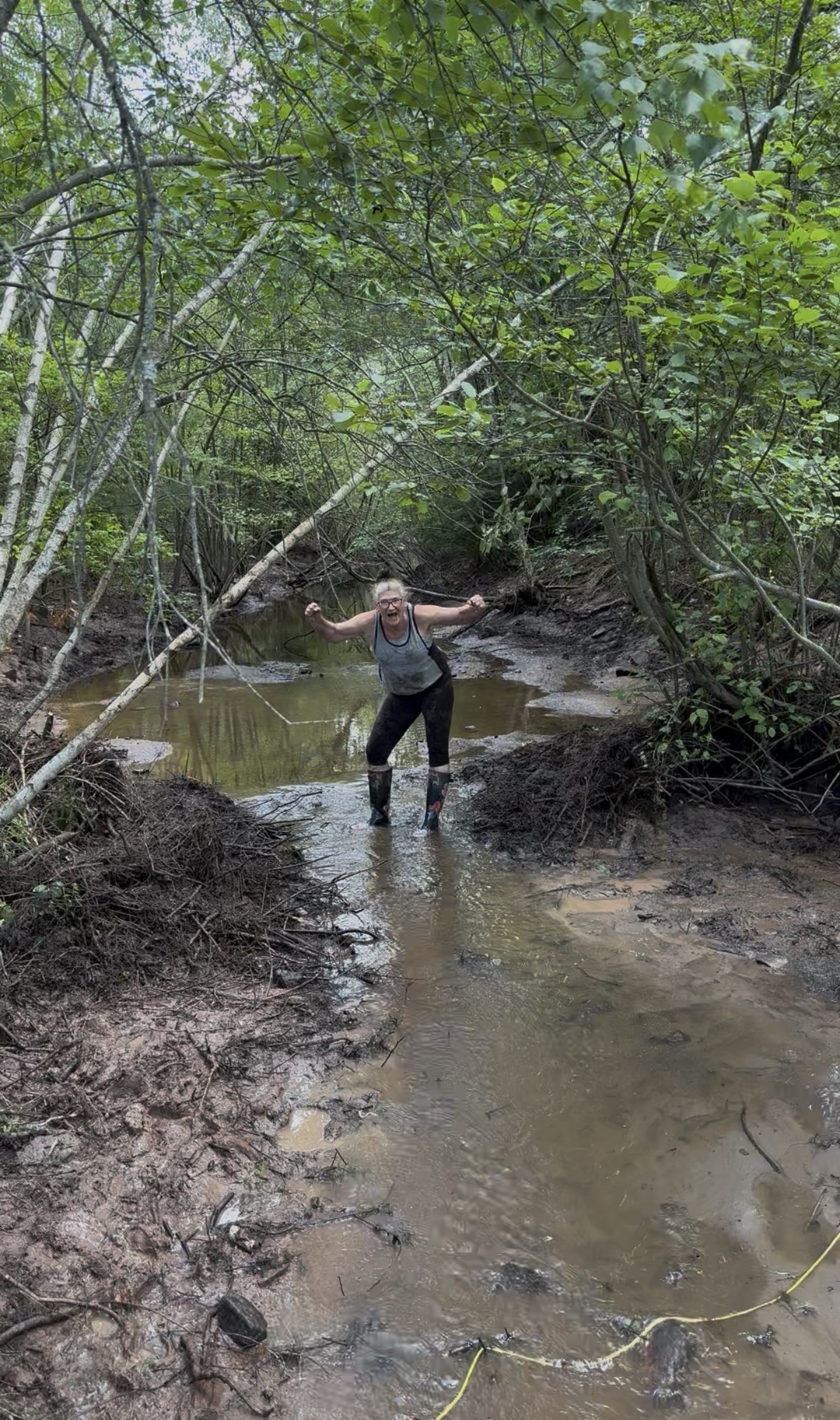Person standing in the stream celebrating after the beaver dam cleanup