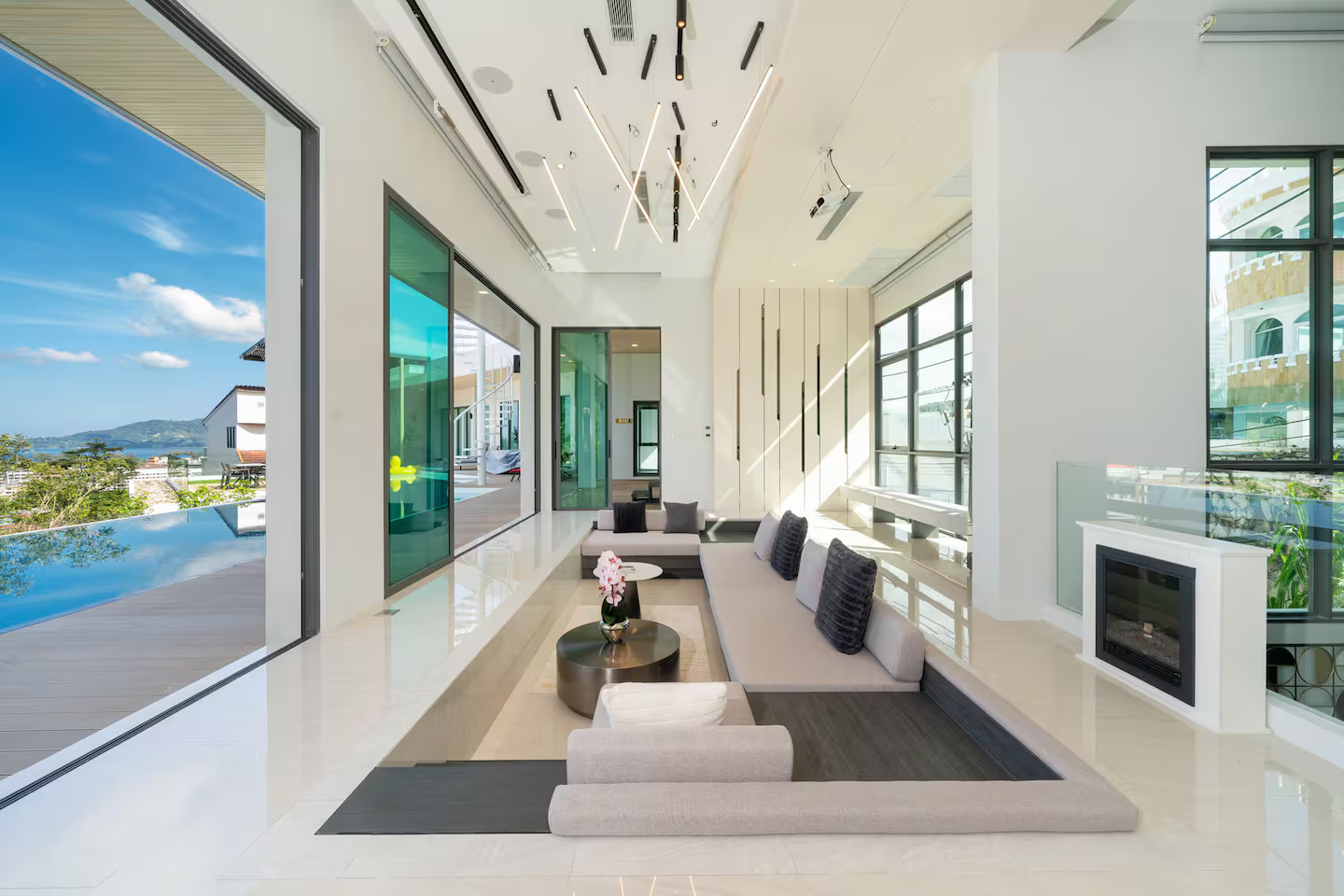 Open-plan living room at Elite Villa Patong, with the pool and sea visible through the glass wall