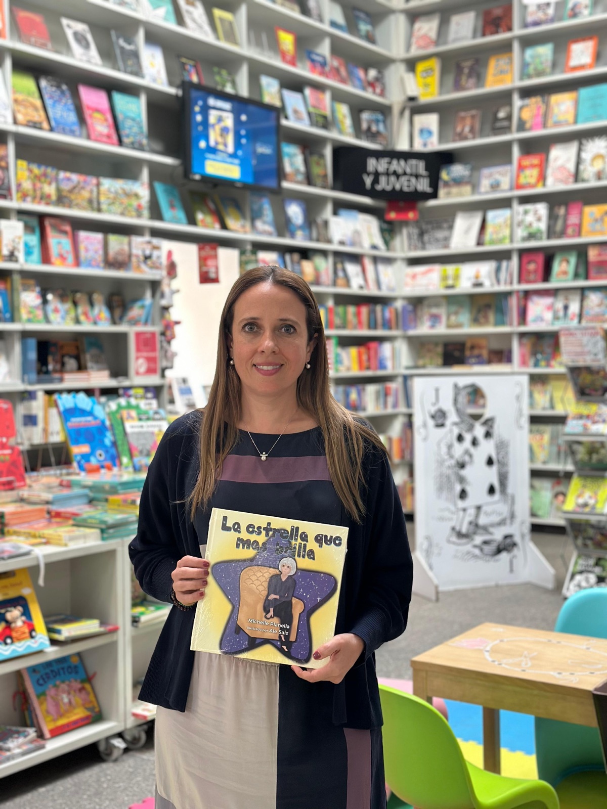 Michelle Planella, autora del cuento, sosteniendo un ejemplar de La estrella que más brilla en una librería