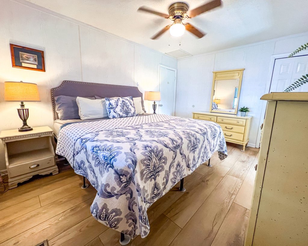 Tufted headboard with blue damask bedding and ceiling fan