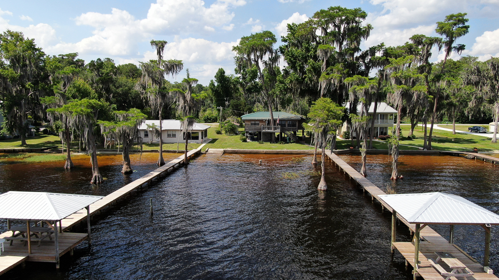 Aerial view of the cabin, docks, and cypress-lined shore