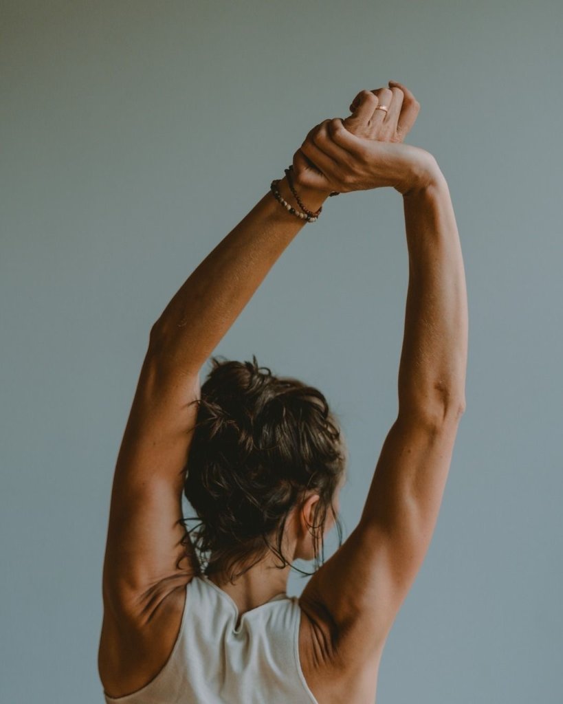 A woman stretching her arms upward during a private movement session