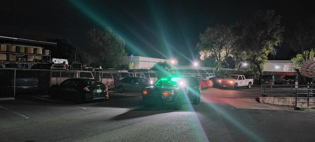 GPI Security marked patrol vehicle with green emergency lights active patrolling a commercial parking lot at night in Sacramento