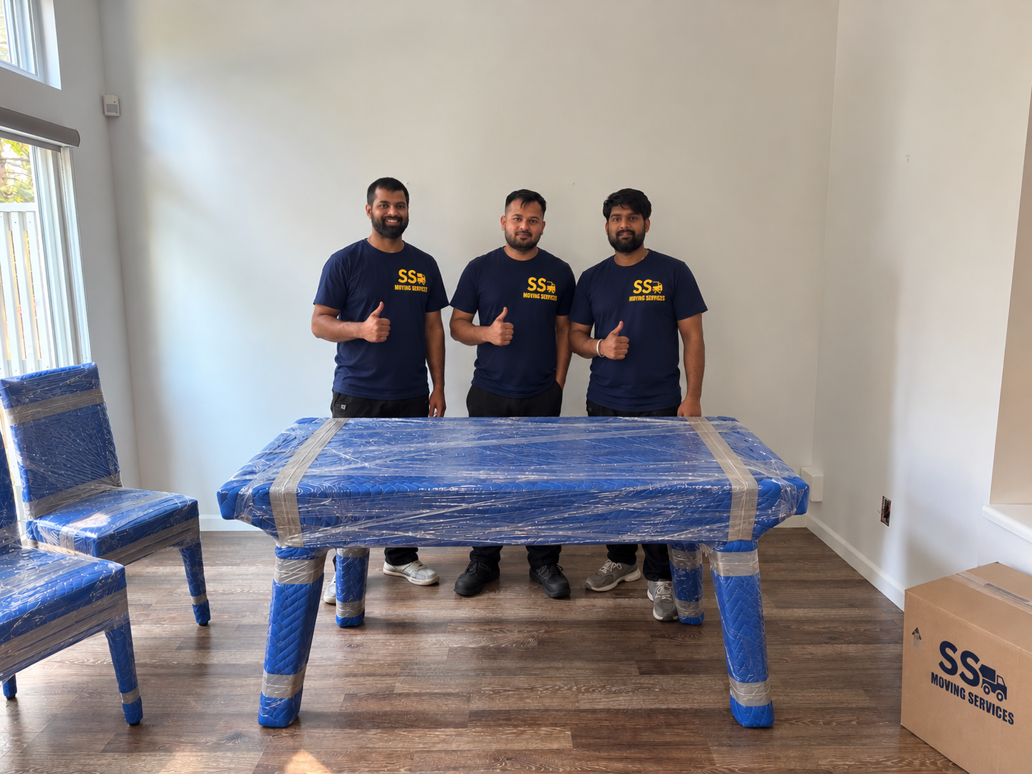 Crew thumbs-up — dining table and chairs wrapped and ready to load