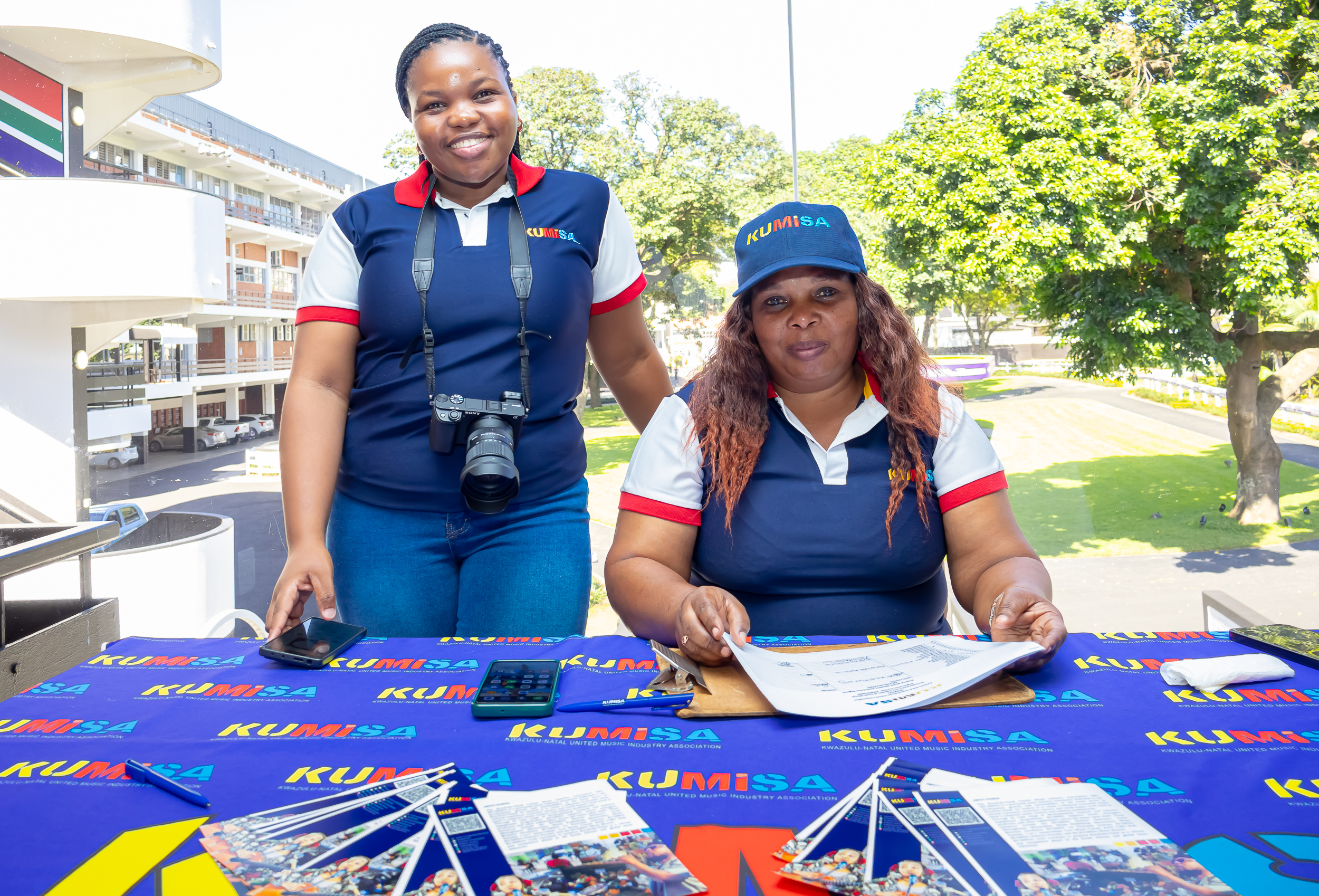 KUMISA team at a community registration desk with branded materials