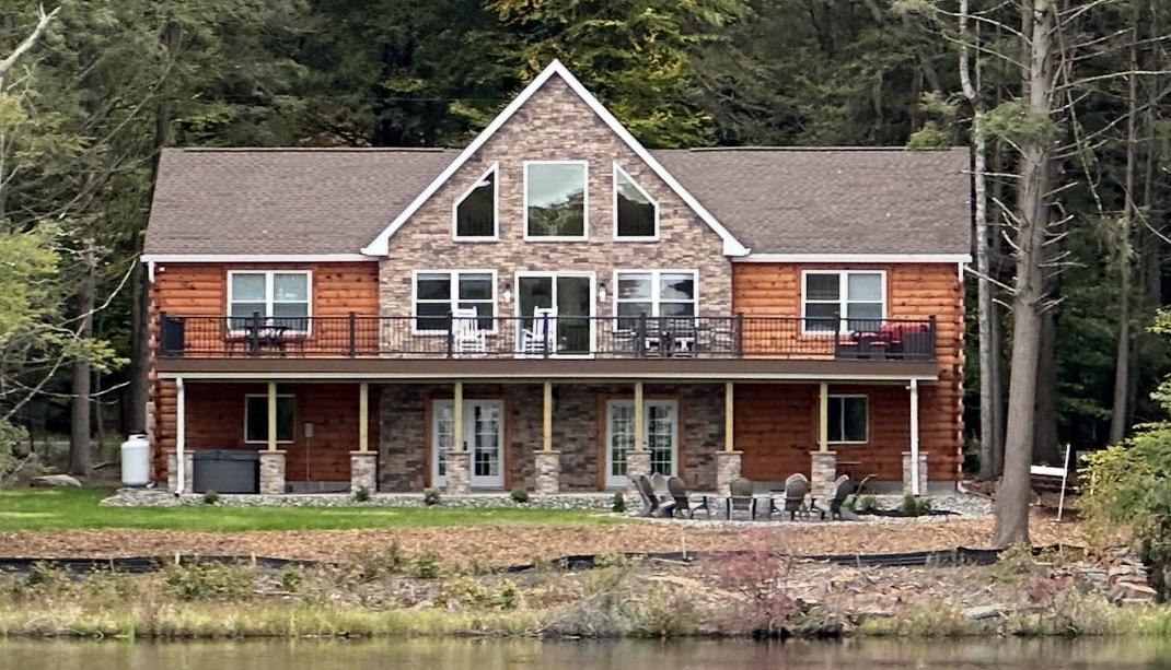 Lakefront log home with stone accents and deck