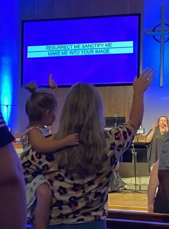 A mother and daughter worshipping together at a Mercy House church service