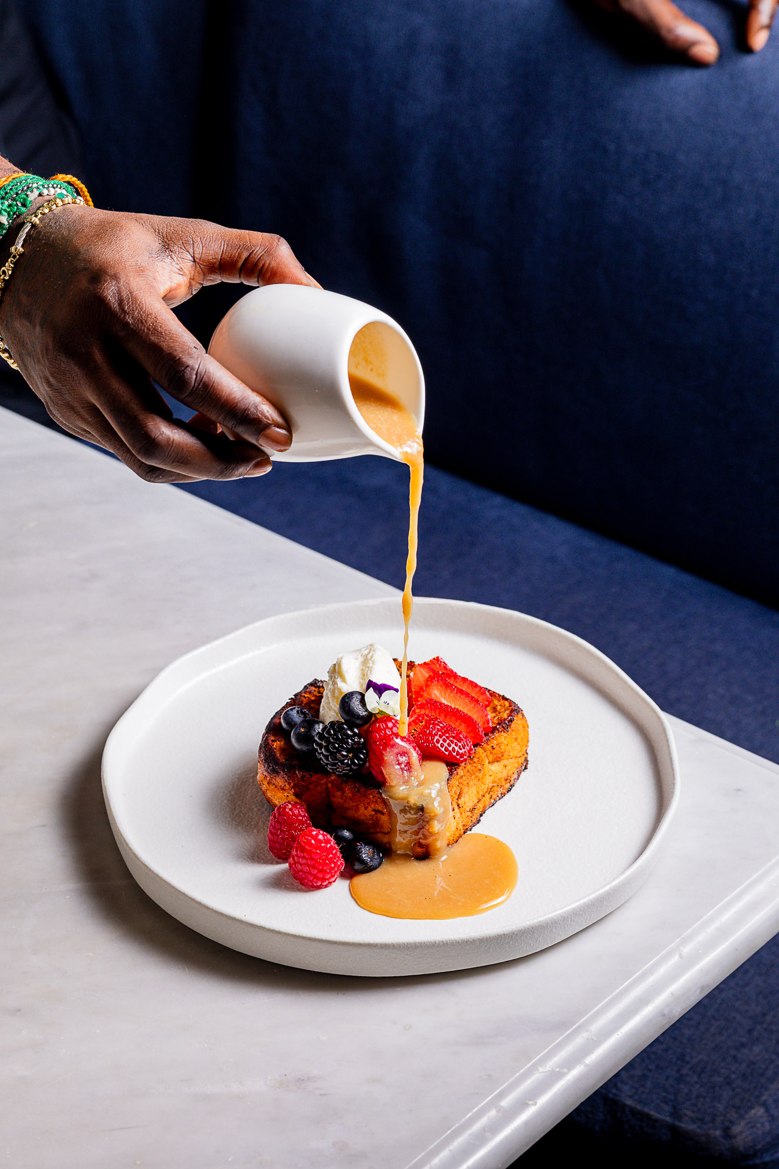 Sauce being poured over French toast with berries at Seventy Seven Alley Tribeca