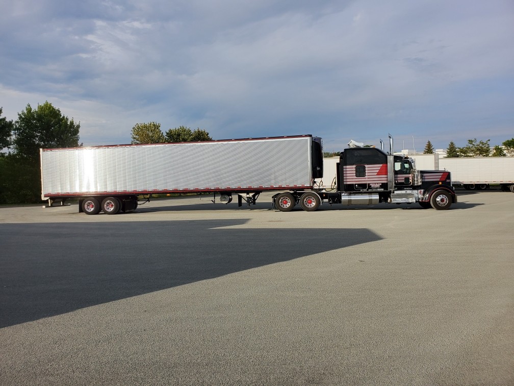 Black tractor with red and white stripes hauling a polished trailer