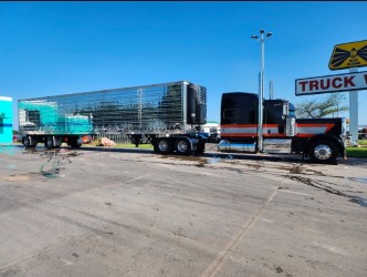 Black and orange tractor with a mirrored refrigerated trailer