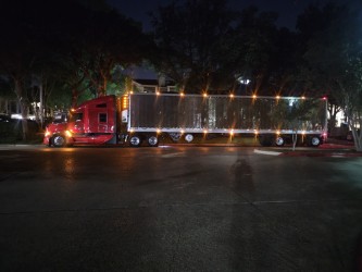 Red tractor with a polished trailer lit at night