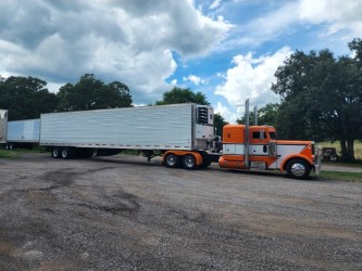 Orange and white tractor pulling a refrigerated trailer